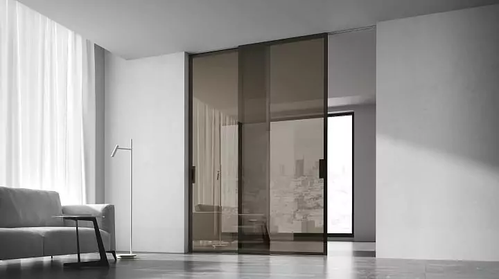 STRATUS–LAGO, translucent Trasparente Grafite glass, aluminum canvas frame in Dark Brown color. Sliding double–leaf partition in the opening, hidden track in the ceiling.